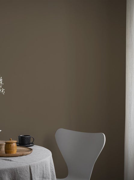 Dekoratives Zimmer mit gemusterter Tapete, Kommode und Sitzhocker