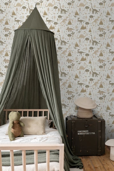 Ein Junge steht vor einer Tapete mit Dinosaurier-Motiv.