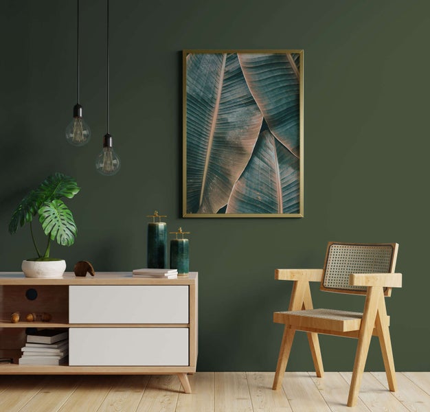 Modernes Wohnzimmer mit dunkelgrüner Wand, Holz-Sideboard, Monstera-Pflanze, gerahmtem Wandbild, Holzstuhl mit Rattangeflecht und Pendelleuchten.