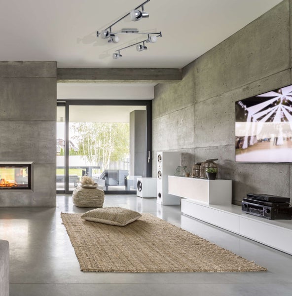 Modernes Wohnzimmer mit Betonwänden, Kamin, Beleuchtungssystem und Teppich
