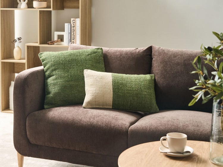 Wohnzimmer Szene mit braunem Sofa und grünen Kissen.