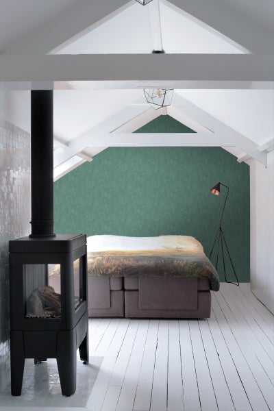 Heller Dachbodenraum mit Kaminofen, Boxspringbett und Stehlampe