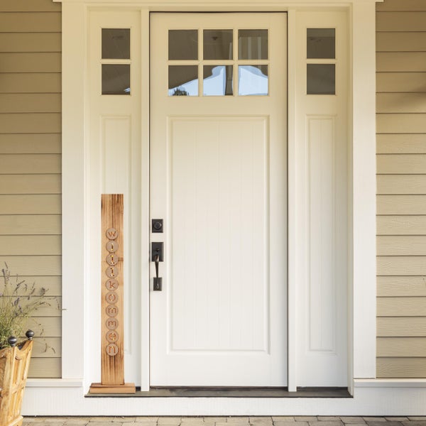 Helle Haustür mit Holzdekoration mit der Aufschrift Willkommen