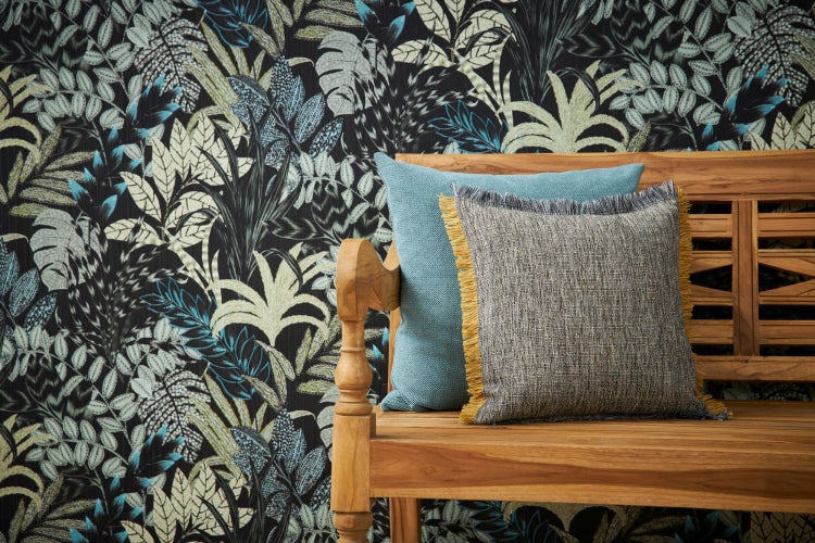 Dekorative Tapete mit Pflanzenmuster und zwei Kissen auf einer Holzbank.