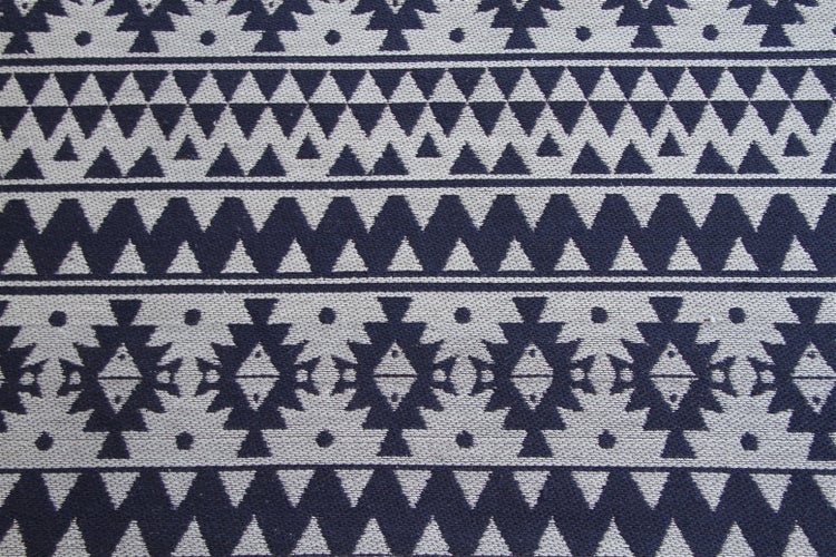 Gewebter Teppich mit geometrischem Ethno-Muster aus Dreiecken und Zickzack-Linien.