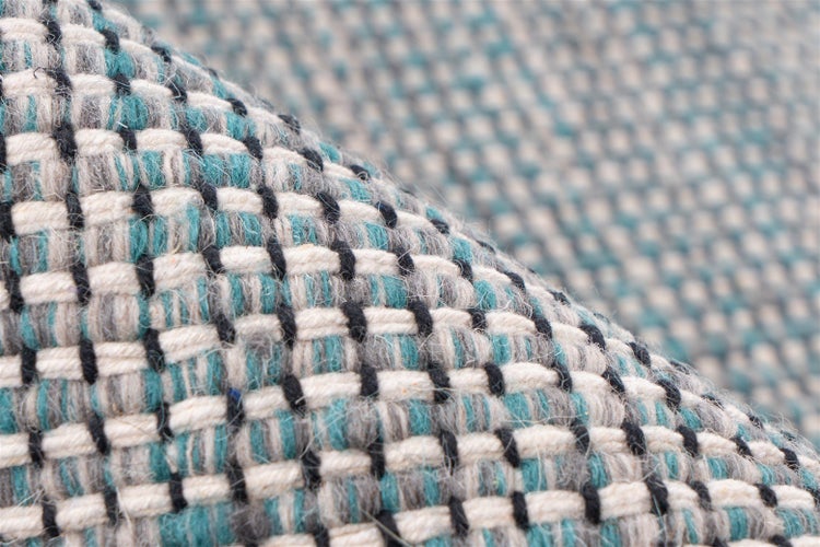Nahaufnahme eines gewebten Teppichs mit Karomuster und grober Oberflächenstruktur.