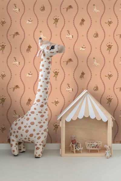 Vliestapete im Kinderzimmer mit Zirkusmotiven, Wellenmuster und Tieren, dazu eine große Plüsch-Giraffe und ein hölzernes Puppenhaus.
