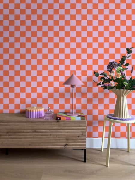 Dekoratives Wohnambiente mit Kommode, Tischleuchte und gemusterter Tapete