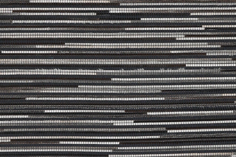 Teppich mit Streifenmuster aus gewebtem Leder in Grau und Schwarz.