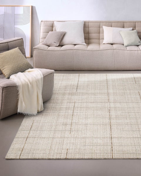 Strukturierter Webteppich mit dezentem Karomuster in einem hellen, modern eingerichteten Wohnzimmer mit Sofa und Sessel.