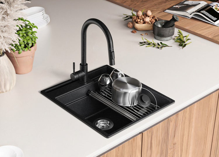 Küchenspüle aus Granit mit Wasserhahn, Abtropfgestell, Geschirr und Kochtopf auf einer Küchentheke