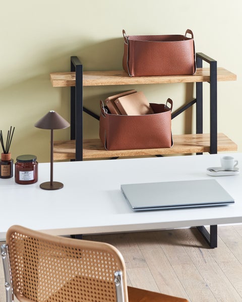 Szene mit Schreibtisch, Regal mit zwei Ablagekörben, Lampe, Duftstäbchen, Kerze, Laptop, Tasse und Stuhl.