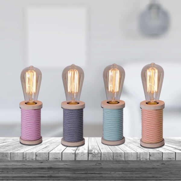 Vier dekorative Tischlampen mit Textilkabel und Glühbirne auf einer Holzoberfläche.