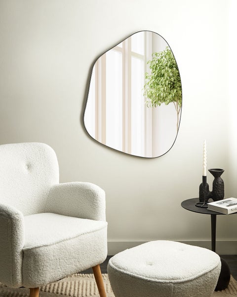 Dekoratives Zimmer mit unregelmäßigem Spiegel, Sessel und Beistelltisch