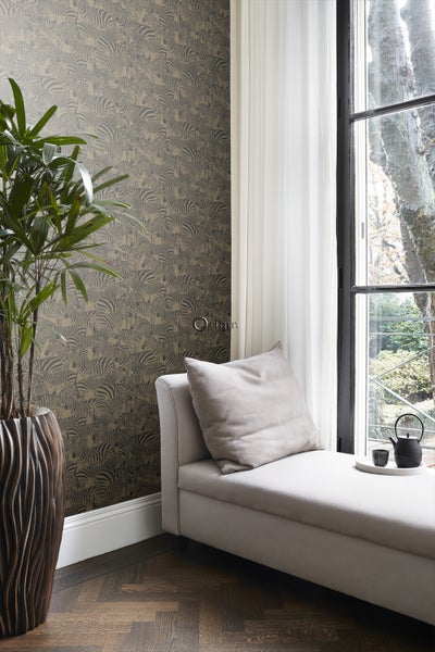Vliestapete mit Zebra-Muster in hellem Zimmer mit Liege, Zimmerpflanze und Parkettboden. Origin Logo.