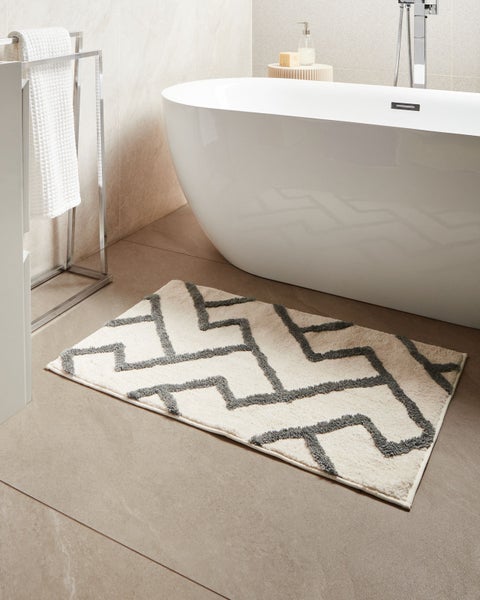 Badezimmer mit Badewanne und Badteppich mit geometrischem Muster