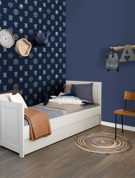 Kinderzimmer mit weißem Bett, Teppich und dekorativer Wandgestaltung.