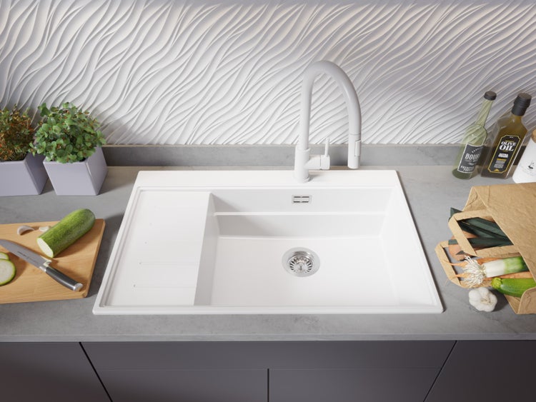 Spüle mit Abtropffläche, Armatur und Lebensmitteln auf einer Küchentheke.