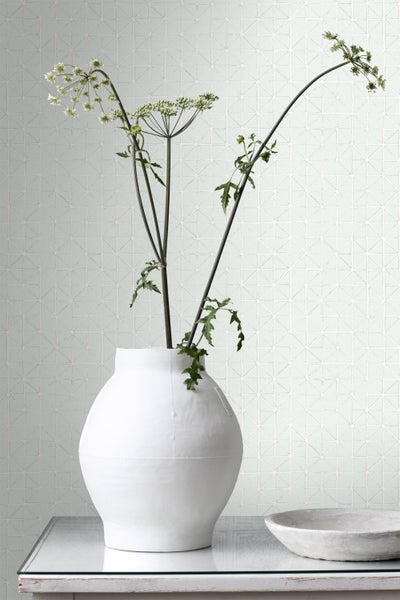 Heller Raum mit Mosaikfliesen an der Wand und einer weißen Vase mit Blumen auf einem Tisch