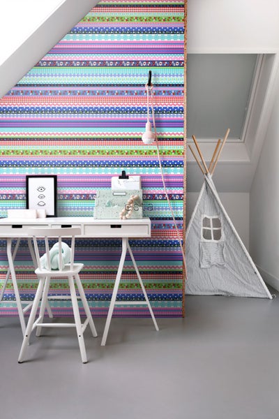 Kinderzimmer mit bunt gestreifter Tapete, Schreibtisch und Spielzelt