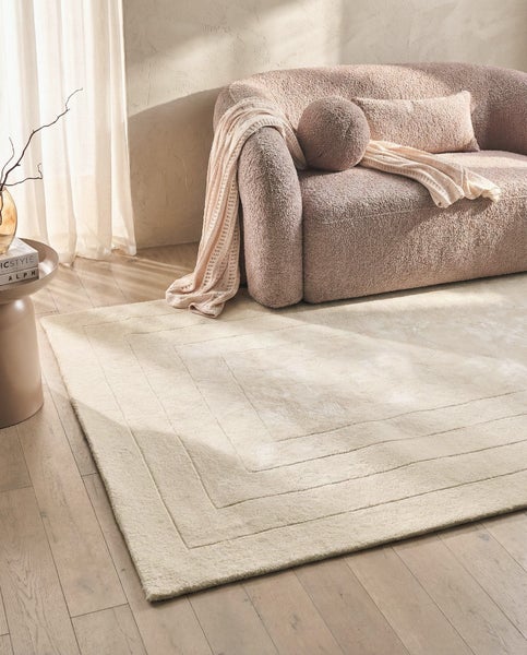 Rechteckiger Teppich mit dezentem Rahmenmuster in Beige.