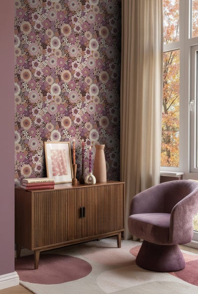 Wohnraum mit geblümter Tapete, Holzkommode und Sessel