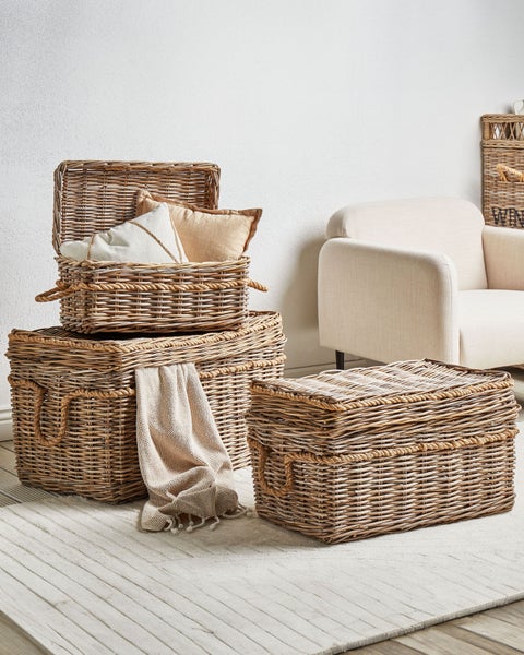 Dekorative Szene mit gestapelten Weidenkörben mit Deckel und Seilgriffen, Textilien und Sessel