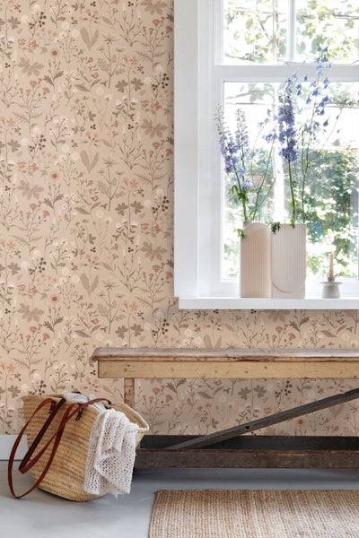 Wohnraum mit Vliestapete mit Blumenmuster in erdigen Tönen, einem weißen Fenster, einer alten Holzbank und einer geflochtenen Tasche.