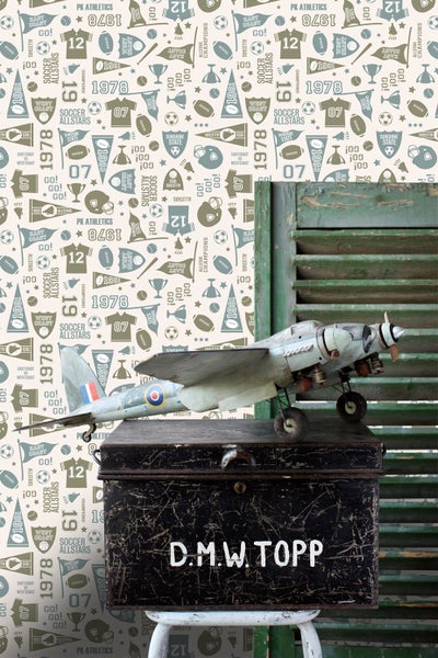 Dekorative Szene mit einem Modellflugzeug auf einer alten Kiste vor einer Wand mit Sportmotiven