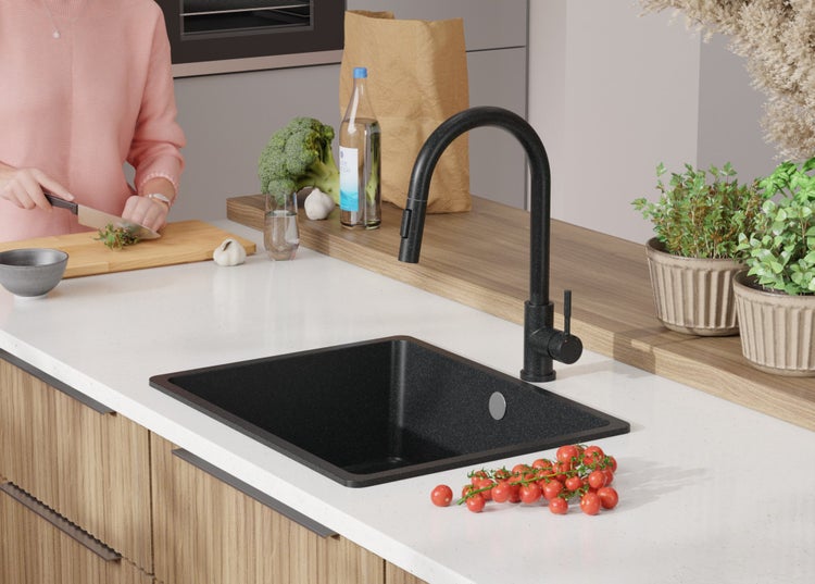 Küchenspüle mit Armatur, Gemüse und Küchenutensilien auf einer Arbeitsplatte.