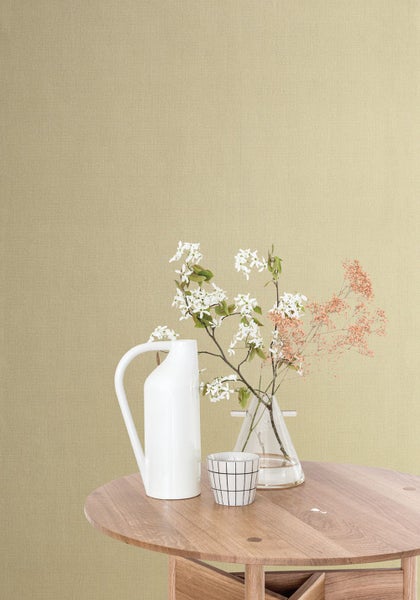 Szene mit Tisch, Vase, Krug, Tasse und Blumen vor einer Wand