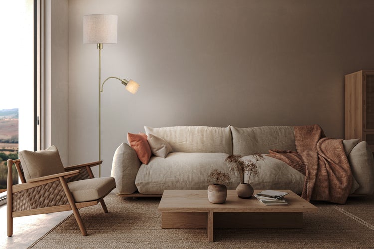 Wohnzimmer mit Sofa, Sessel, Stehlampe und Couchtisch auf einem Teppich