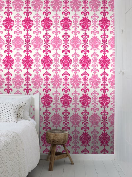 Raumansicht mit pinkfarbener Ornamenttapete, Bett und Hocker