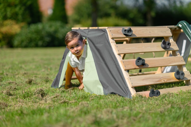 Kind spielt auf einem Holzspielplatz mit Kletterwand und Zeltfunktion im Garten