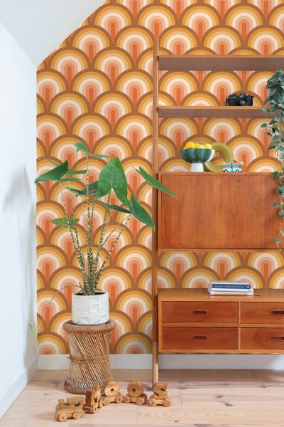 Innenraum mit Retro-Tapete mit Halbkreis-Muster, Holzregal, Zimmerpflanze im Topf und Holzspielzeug auf dem Boden.