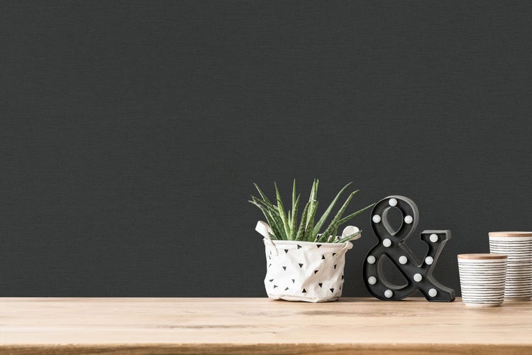 Einrichtungsbeispiel mit Sessel, Beistelltisch und Hängelampe vor dunkler Wand