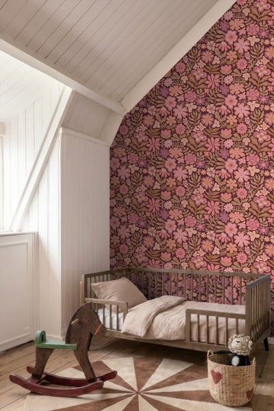 Kinderzimmer mit floral gemusterter Tapete, einem Holzbett mit Betthimmel, einem Nachttisch und einer geflochtenen Hängelampe.