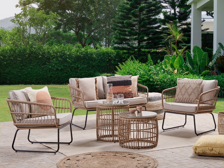 Outdoor-Loungegruppe mit Rattansesseln, Sofa und Beistelltischen auf einer Terrasse