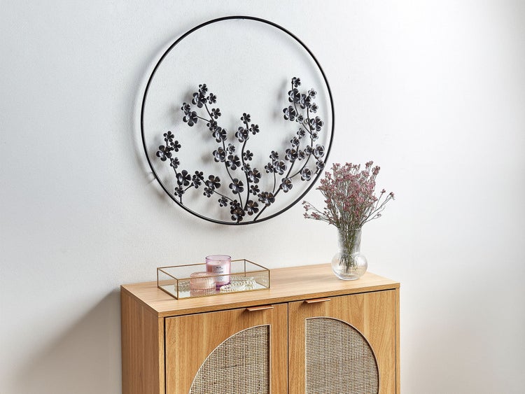 Dekorative Szene mit einer Wanddekoration mit Blumenmuster, einer Kommode, einer Duftkerze und einer Blumenvase.