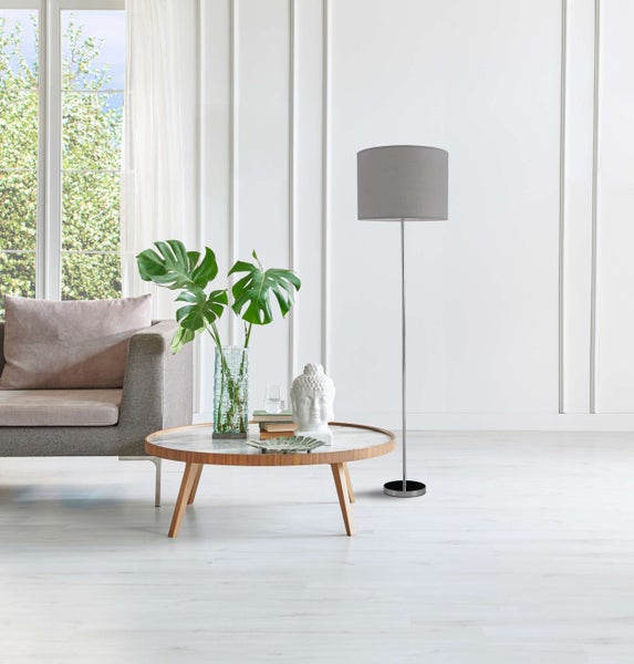 Helles Wohnzimmer mit Sofa, Couchtisch, Stehlampe und Fenster