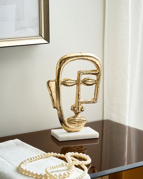 Dekorative goldfarbene Gesichtsskulptur auf Marmorsockel