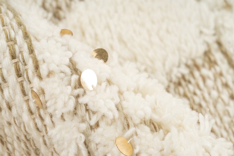 Detailaufnahme eines grob gewebten Textils mit dekorativen metallischen Pailletten.