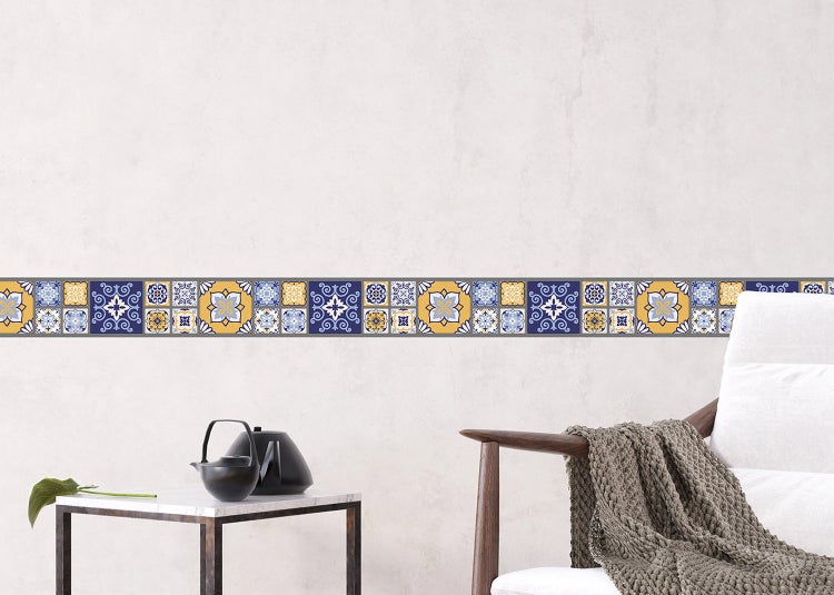 Wandbordüre mit mediterranem Fliesenmuster in einem hellen Wohnzimmer mit Tisch und Sessel.