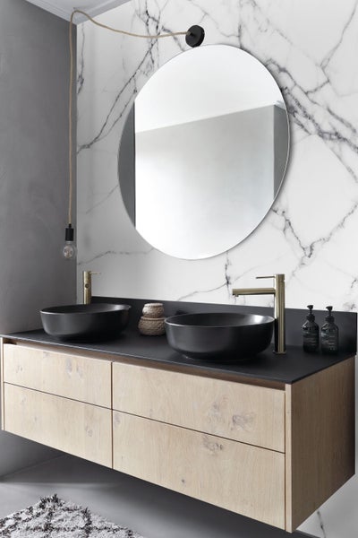 Badezimmer mit Doppelwaschtisch, runder Spiegel und moderner Beleuchtung