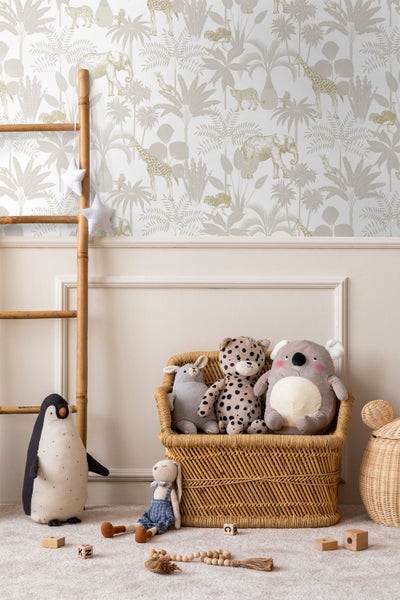 Vliestapete mit Safari-Motiven wie Elefanten, Giraffen und Palmen in einem hell gestalteten Kinderzimmer mit Stofftieren.