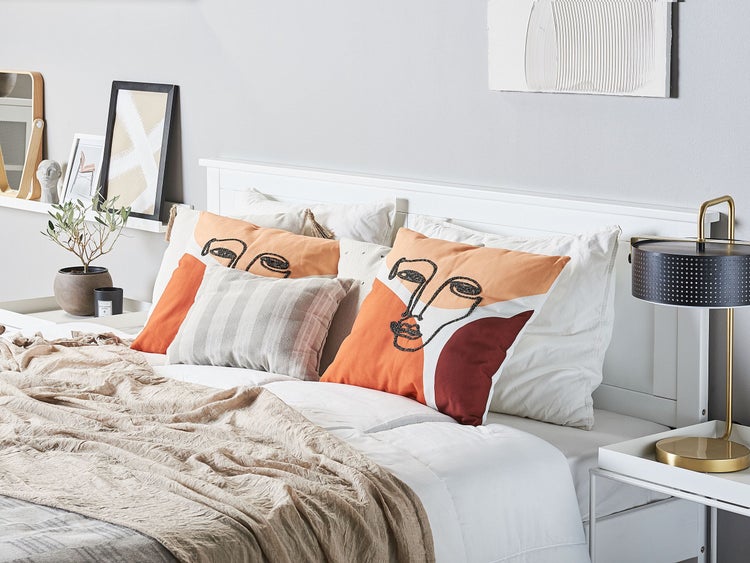 Schlafzimmer mit Bett, Kissen mit Gesichtsmuster, Nachttischlampe und Dekoration