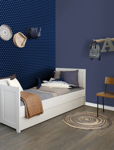 Kinderzimmer mit weißem Bett, Wanddekoration und rundem Teppich