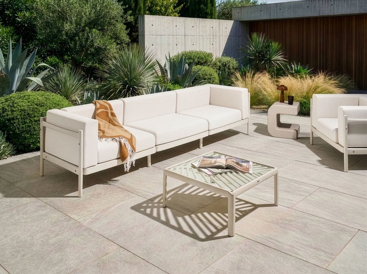 Gartenszene mit modularem Sofa, Sessel und Couchtisch auf einer Terrasse