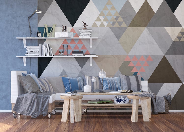 Wohnzimmer mit Sofa, Couchtisch und Regal vor einer geometrischen Tapete