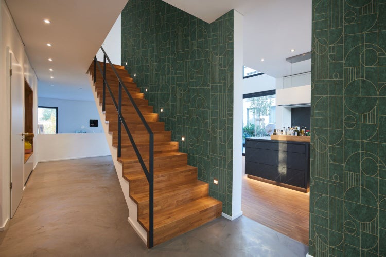 Frau sitzt an einem Schreibtisch mit einer Schreibtischlampe und einem Computerbildschirm in einem Büro.